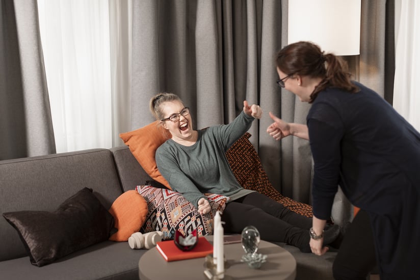 Kvinna sitter i soffan och gör tummen upp till en kvinna