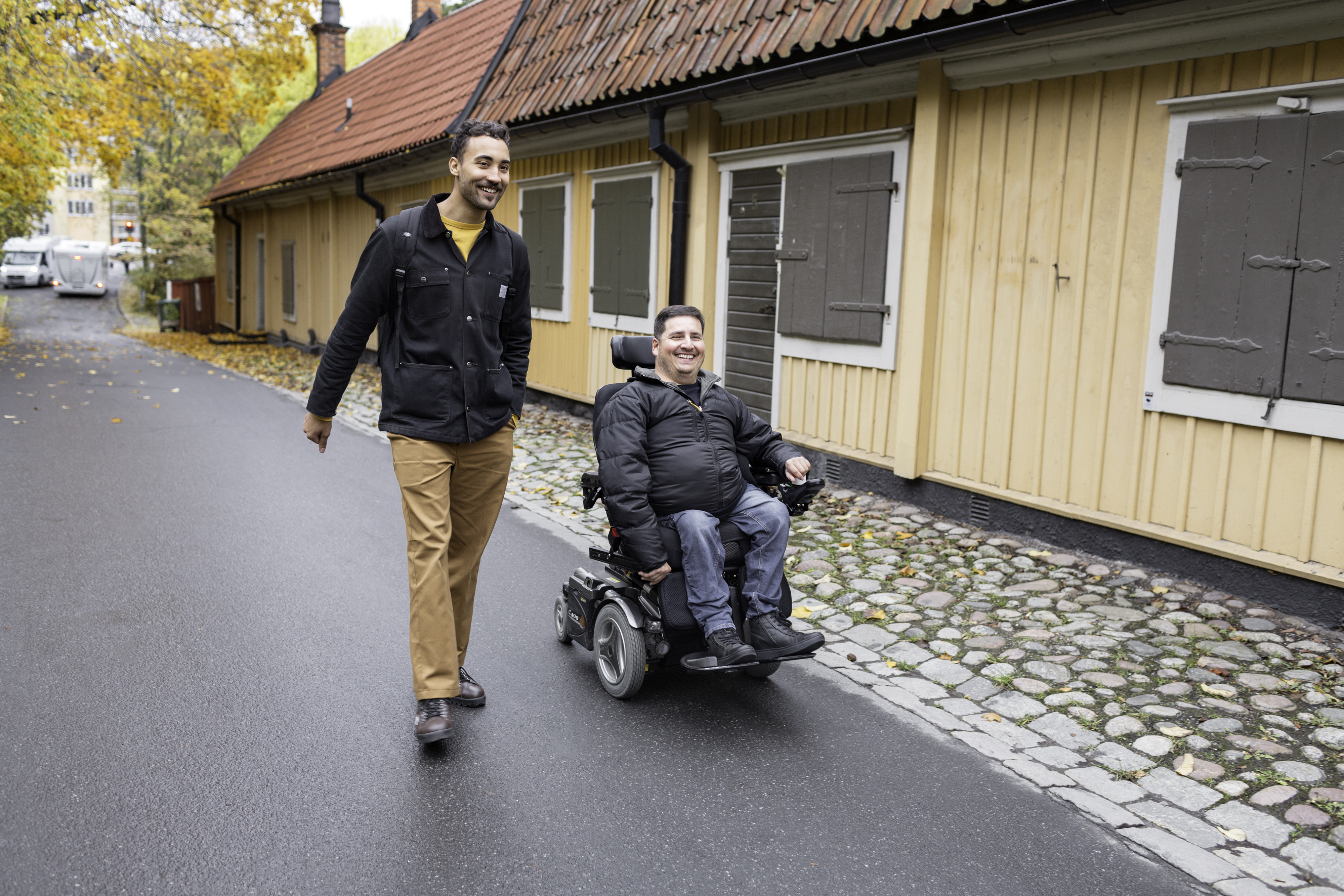 personlig assistent går bredvid rullstolsburen assistansanvändare